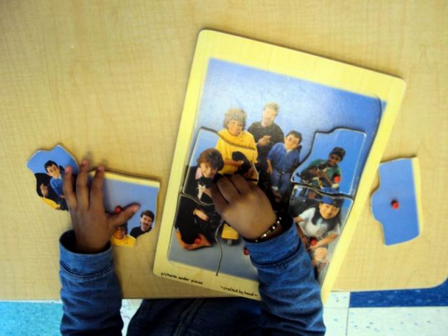 child working on a multiple piece single picture puzzle