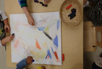 Children under 3 working on oil pastel scribble art 