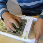 Casa child grating a zucchini