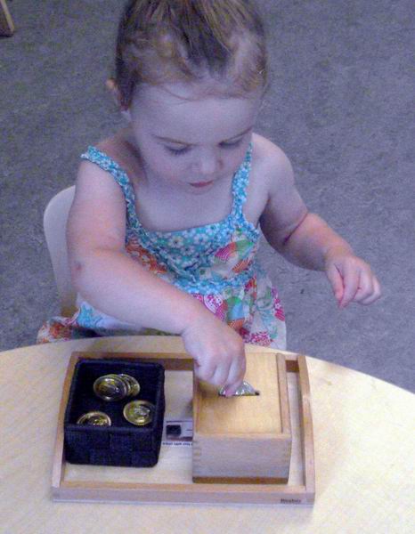 Child under 3 inserting a coin into slotted box