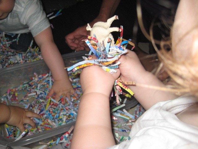 Child under 2 holding an animal and shredded paper