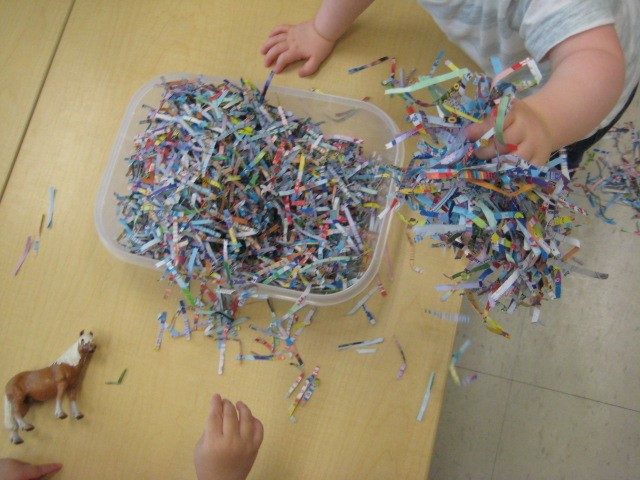 Child under 2 holding shredded paper 