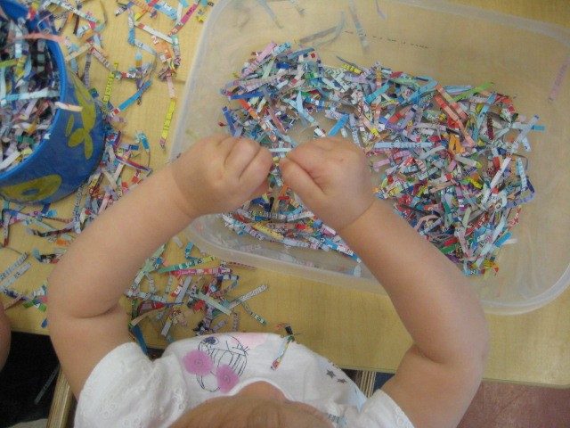 Child under 2 exploring shredded paper 