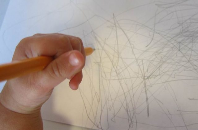 hand of a child under 2, drawing with a pencil