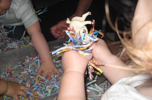 Child's hands holding animal in shredded paper