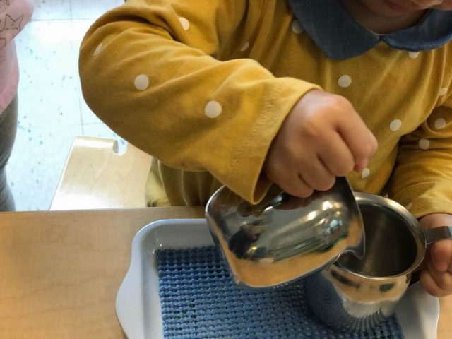 Child pouring water from creamer to creamer