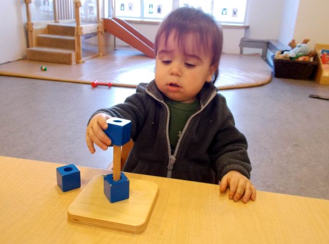 Child Under 2 placing a cube on a dowel