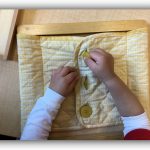 Child under 3 working on button dressing frame