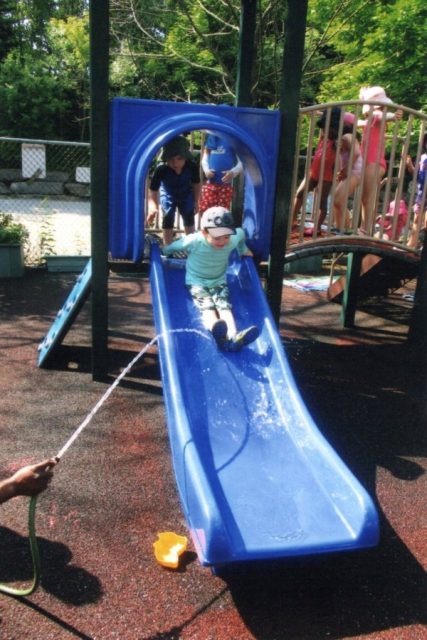 Child sliding down a wet slide