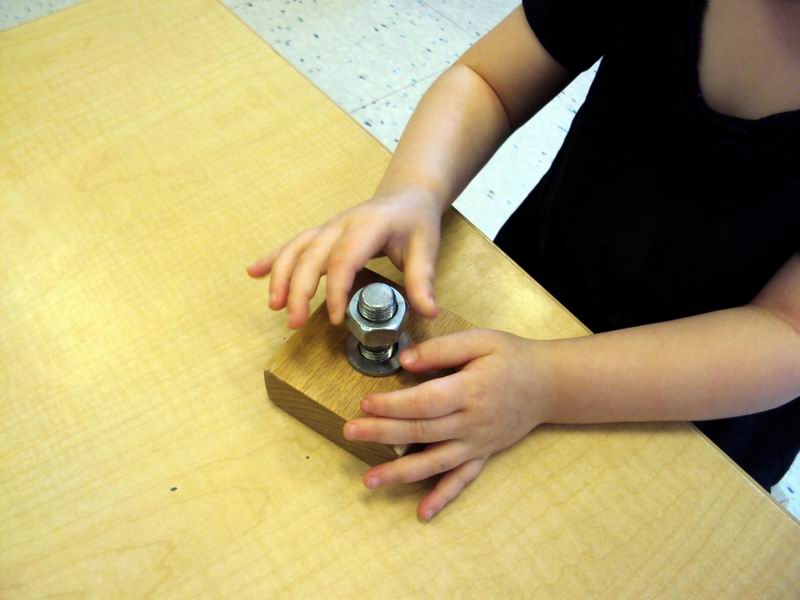 Child working on a bolt and nut