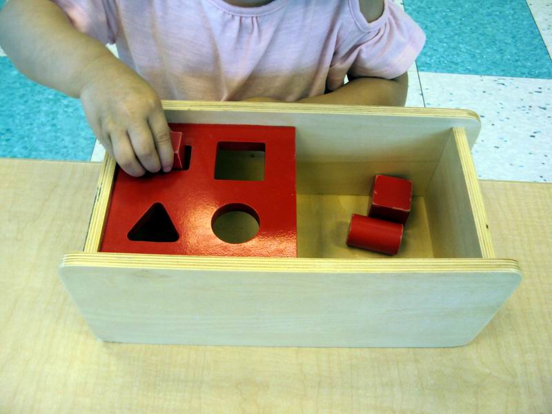 Child inserting geometric solids into a shape sorter