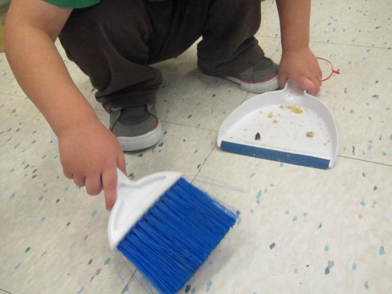 A child using a sweeper and dustpan