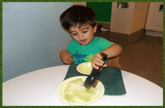Child under 2 using tongs to serve fruit
