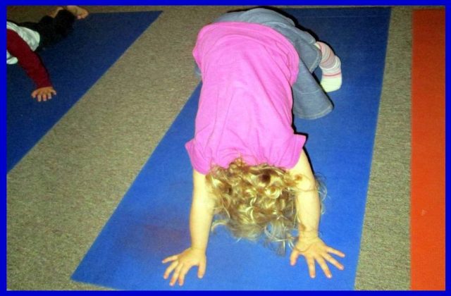 Child practicing the 'downward dog' pose in yoga