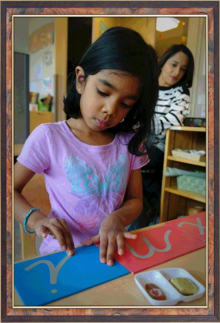 Casa parent observing child tracing cursive sandpaper letters