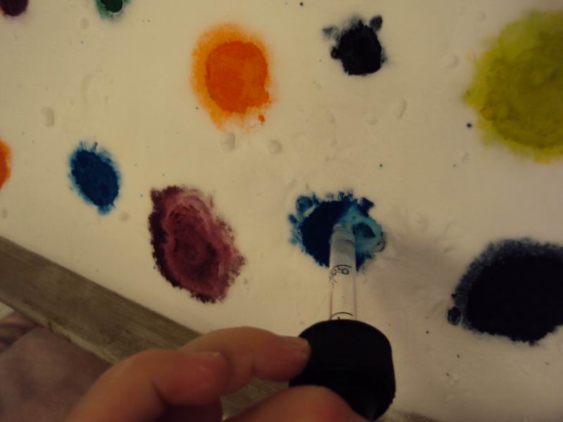 A child's hand dropping vinegar onto the baking soda mixture