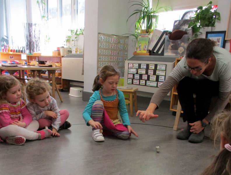 A parent showing children how to spin a dreidel