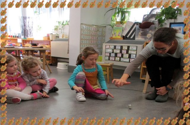 A parent showing children how to spin a dreidel