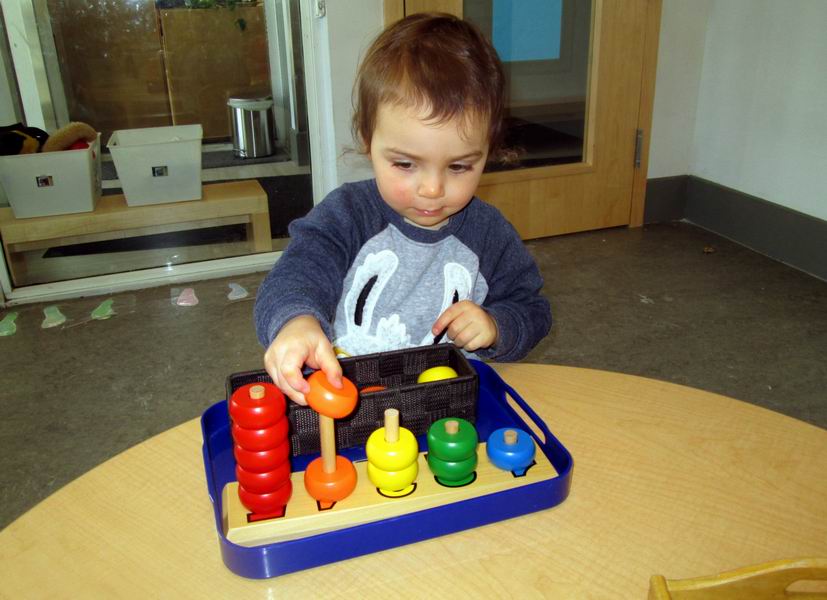 Child placing coloured rings on dowels