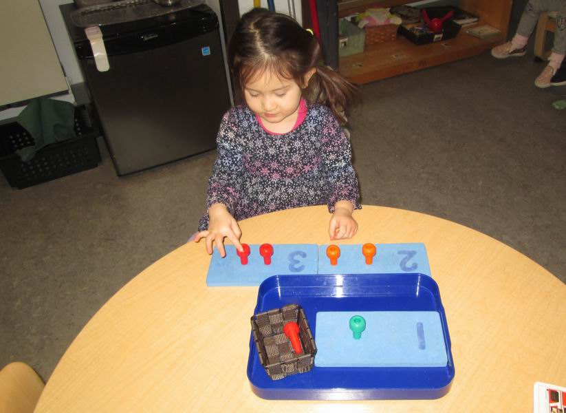 Child placing coloured pegs in math boards