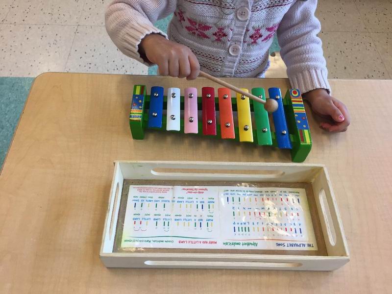 Child playing a xylophone with sheet music