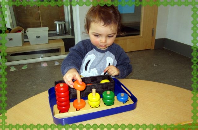 Child placing coloured rings on dowels