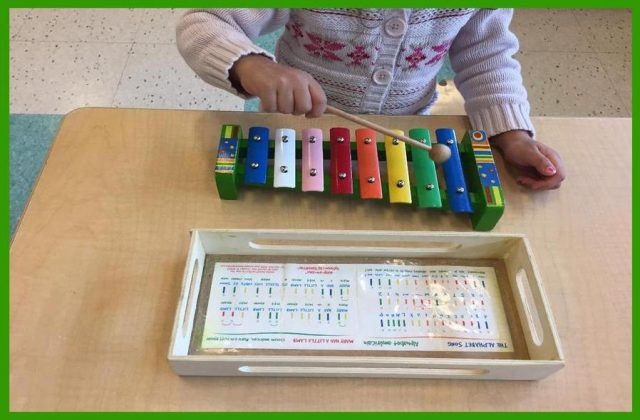 Child playing a glockenspiel with sheet music