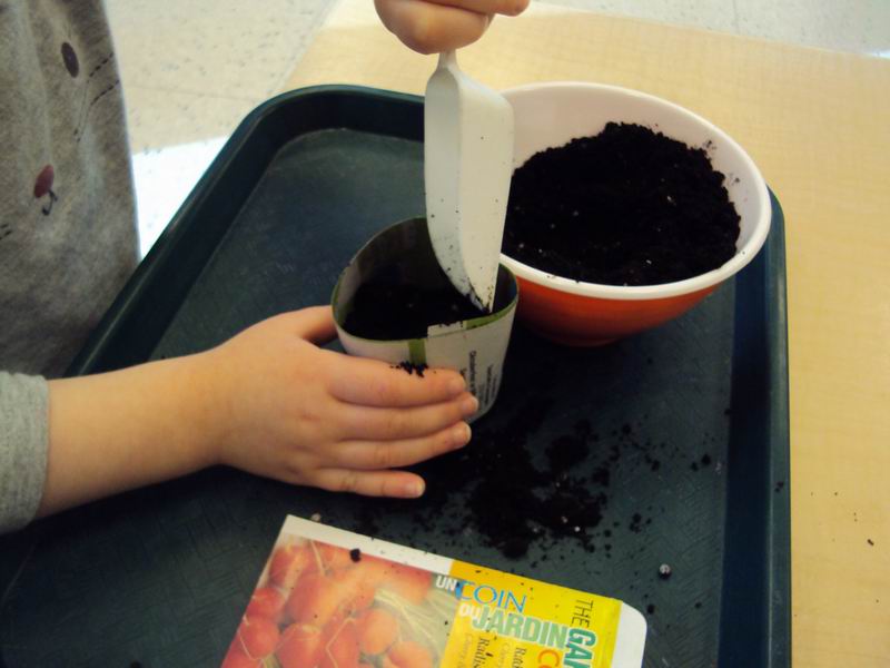 A child filling a biodegradable planter with soil