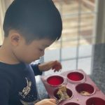 child scooping blueberry muffin mixture
