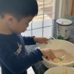 child adding wet ingredients to dry ingredients