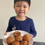 child holding plate of blueberry muffins