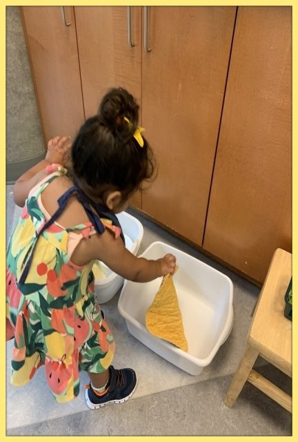 Child under 2 putting her placemat in the laundry bin