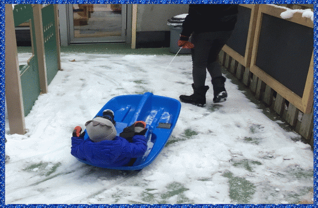 A child being pulled on a sled in the snow