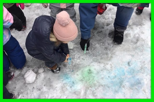 Child under 3 spraying coloured water in the snow