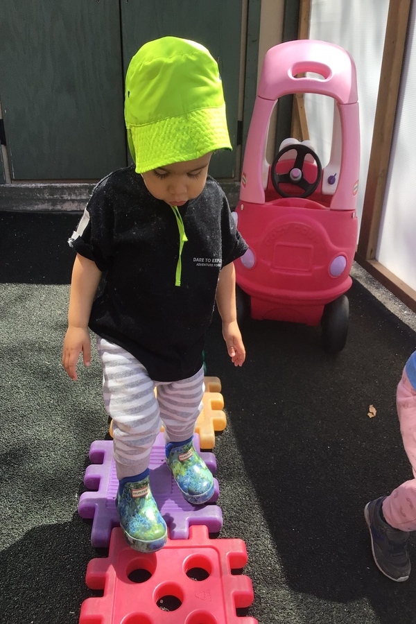 An infant walking on a waffle block path