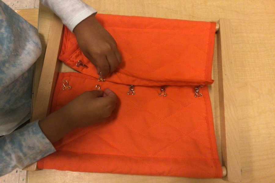 A child working with a hook and eye dressing frame