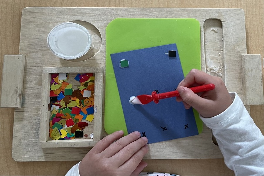 A child gluing shapes onto a paper