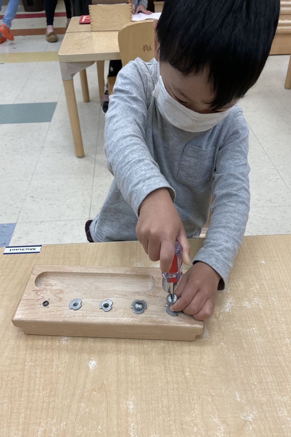 A child using a screwdriver and screws