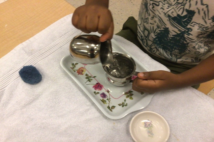 A child pouring water from creamer to creamer