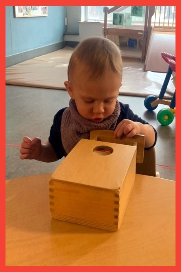 A child opening a drawer in a box to look for a ball