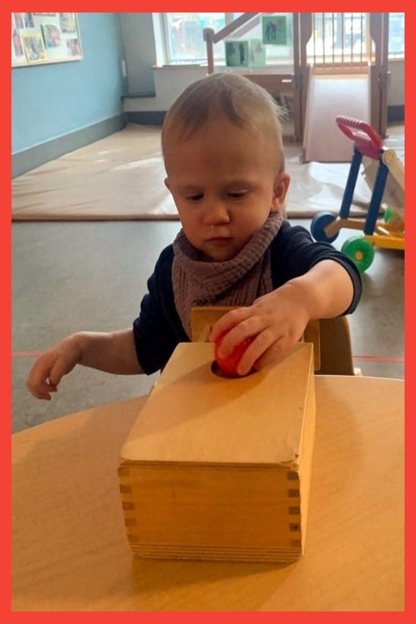 A child dropping a ball into a box with drawer