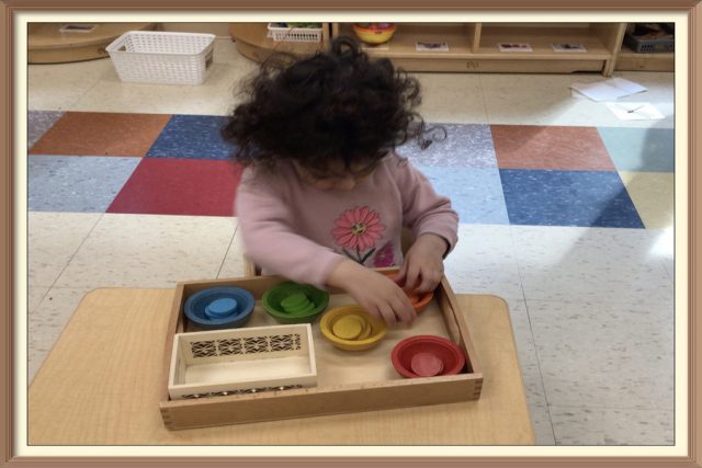 A child placing an orange disc in a small orange bowl