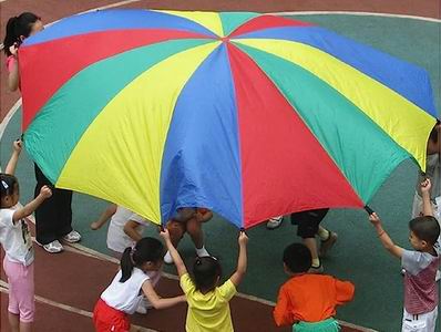 Children throwing up a parachute with other children underneath