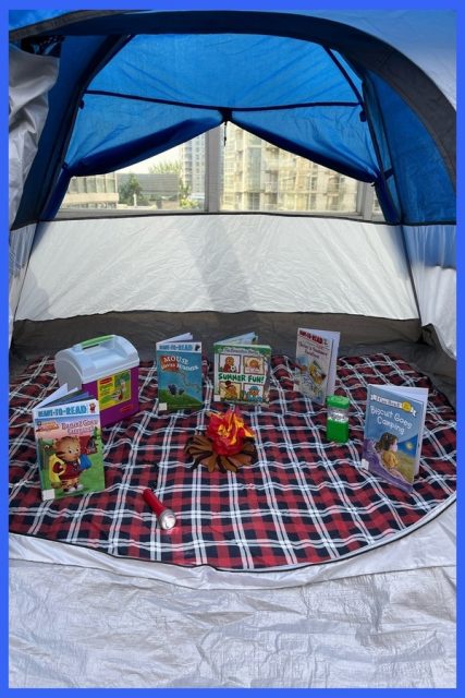 A close-up of books, a flashlight, a pretend camp fire in a tent