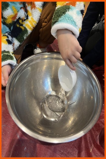 A child pouring ingredients into a bowl