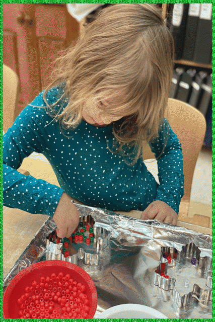 A child placing coloured pony beads inside a metal cookie cutter