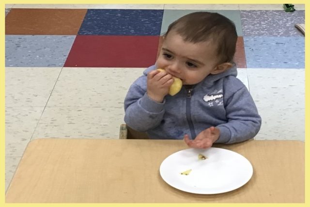 A child tasting a juicy piece of pineapple