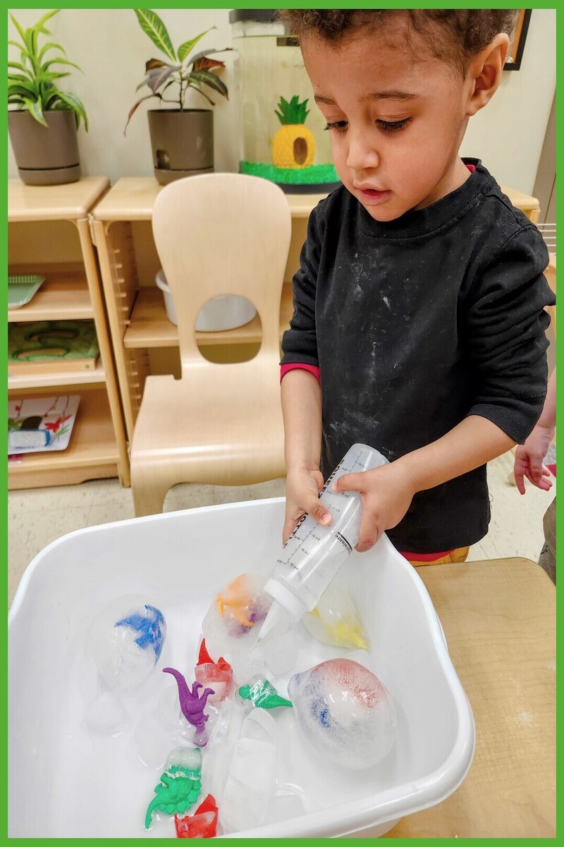 A child squirting warm water on dinosaur ice eggs