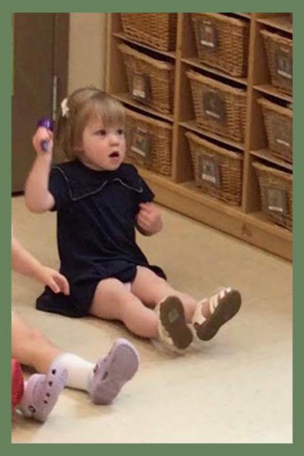 A child shaking an instrument during music class