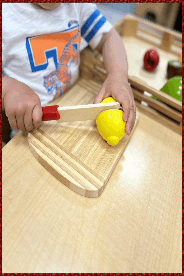 A child cutting a velcro lemon in half with a wooden knife